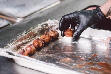 Tema yemek. Ellerini kapatın. Beyaz delikanlı mutfakta siyah üniforma ve lateks eldiven. Restoran kıyma hazırlar ve berry şırınga ile yol açar. İncir, incir veya Karya ficus çanak.