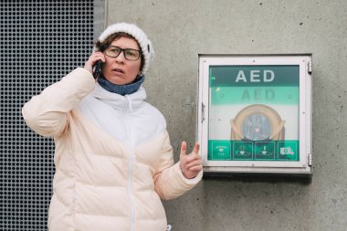 Tıp Kardiyopulmoner resüsitasyon acil çağrı yapıyorum. Kafkas kadın 911 yardım aramakta telefon kullanır. Cihaz kutusu aed otomatik defibrilatör hastalıkları, klinik ölüm, kalp durması ve kalp krizi