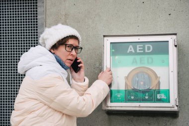 Tıp Kardiyopulmoner resüsitasyon acil çağrı yapıyorum. Kafkas kadın 911 yardım aramakta telefon kullanır. Cihaz kutusu aed otomatik defibrilatör hastalıkları, klinik ölüm, kalp durması ve kalp krizi