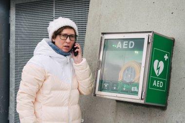 Tıp Kardiyopulmoner resüsitasyon acil çağrı yapıyorum. Kafkas kadın 911 yardım aramakta telefon kullanır. Cihaz kutusu aed otomatik defibrilatör hastalıkları, klinik ölüm, kalp durması ve kalp krizi