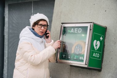 Tıp Kardiyopulmoner resüsitasyon acil çağrı yapıyorum. Kafkas kadın 911 yardım aramakta telefon kullanır. Cihaz kutusu aed otomatik defibrilatör hastalıkları, klinik ölüm, kalp durması ve kalp krizi