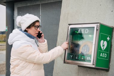 Tıp Kardiyopulmoner resüsitasyon acil çağrı yapıyorum. Kafkas kadın 911 yardım aramakta telefon kullanır. Cihaz kutusu aed otomatik defibrilatör hastalıkları, klinik ölüm, kalp durması ve kalp krizi