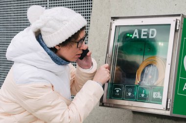Tıp Kardiyopulmoner resüsitasyon acil çağrı yapıyorum. Kafkas kadın 911 yardım aramakta telefon kullanır. Cihaz kutusu aed otomatik defibrilatör hastalıkları, klinik ölüm, kalp durması ve kalp krizi