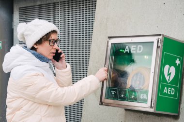 Tıp Kardiyopulmoner resüsitasyon acil çağrı yapıyorum. Kafkas kadın 911 yardım aramakta telefon kullanır. Cihaz kutusu aed otomatik defibrilatör hastalıkları, klinik ölüm, kalp durması ve kalp krizi
