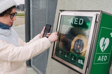 Tıp Kardiyopulmoner resüsitasyon acil çağrı yapıyorum. Kafkas kadın 911 yardım aramakta telefon kullanır. Cihaz kutusu aed otomatik defibrilatör hastalıkları, klinik ölüm, kalp durması ve kalp krizi