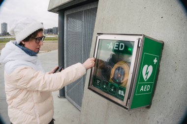 Tıp Kardiyopulmoner resüsitasyon acil çağrı yapıyorum. Kafkas kadın 911 yardım aramakta telefon kullanır. Cihaz kutusu aed otomatik defibrilatör hastalıkları, klinik ölüm, kalp durması ve kalp krizi