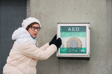 Tıp Kardiyopulmoner resüsitasyon ve acil arama. Genç Kafkas kadın yardım istiyor. Cihaz kutusu aed otomatik defibrilatör hastalıkları, klinik ölüm, kalp durması ve kalp krizi.