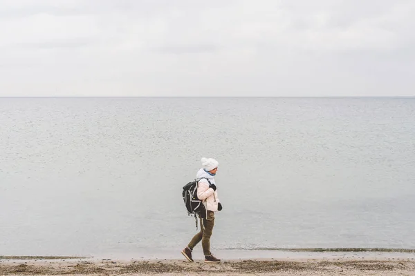 Один кавказский мужчина молодая кавказка туристка с черным рюкзаком на песчаном пляже у Балтийского моря зимой. Тематическое путешествие в одиночку. Мысли и мечты с видом на горизонт — стоковое фото