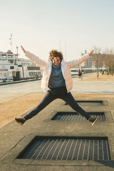 adult person rejoices like child. Playground trampoline in ground, children trampoline, springs throws people up fun and cool. Copenhagen River Embankment Denmark. Woman jumping on street trampoline