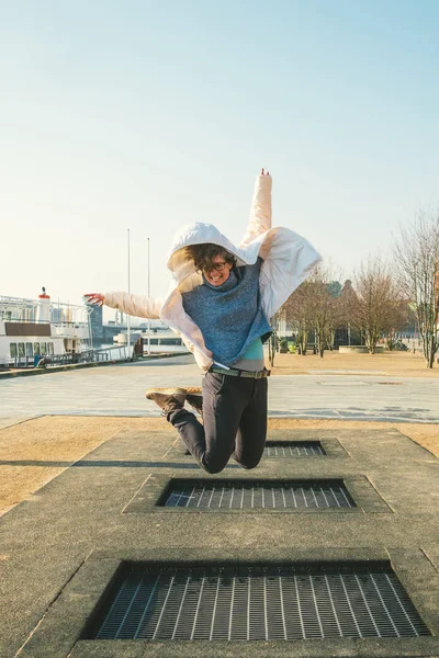 adult person rejoices like child. Playground trampoline in ground, children trampoline, springs throws people up fun and cool. Copenhagen River Embankment Denmark. Woman jumping on street trampoline