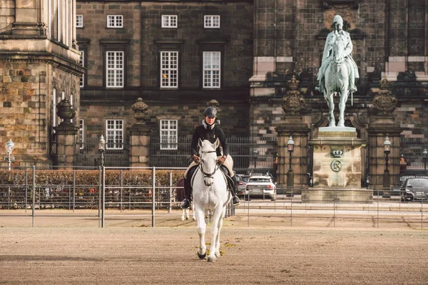 stock image February 20, 2019. Denmark. Copenhagen. Training bypass Adaptation of a horse in the royal stable of the castle Christiansborg Slots. Man rider in uniform and helmet and racehorse outdoors