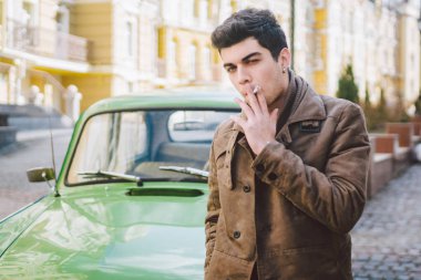 Esmer Türk Orta Doğu esmer bir sigara sokaktaki eski retro car yakınındaki poz ile bir modeli genç yakışıklı seksi erkek esmer bir adam portresi