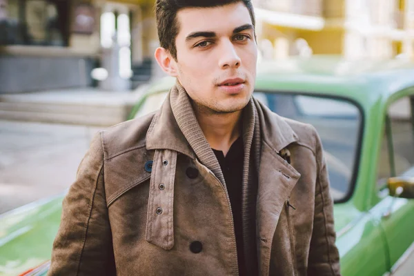 Portrait of a model young handsome sexy male brunette guy with dark skin Turkish Middle Eastern brunette posing smoking a cigarette near old retro car on the street — Stock Photo, Image