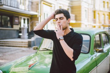 Esmer Türk Orta Doğu esmer bir sigara sokaktaki eski retro car yakınındaki poz ile bir modeli genç yakışıklı seksi erkek esmer bir adam portresi