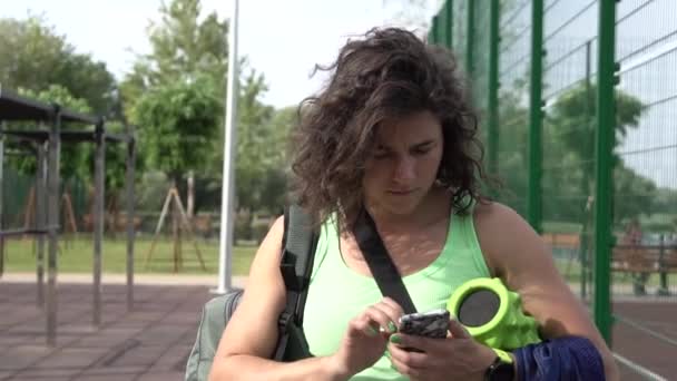 Vrouw met behulp van slimme telefoon voor SMS bericht lezen. In achtergrond fitnessapparatuur. Gezonde levensstijl concept — Stockvideo