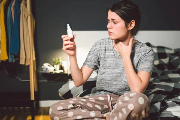 El tema es el resfriado estacional, la infección por el virus de la gripe nasal. Mujer caucásica joven en la cama del dormitorio en casa utiliza gotas de aerosol de medicina en la nariz para mocos. Renitis alérgica y sinusitis — Foto de Stock