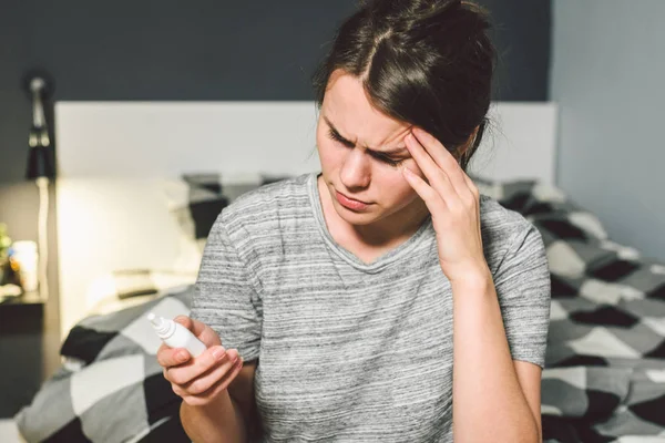 El tema es el resfriado estacional, la infección por el virus de la gripe nasal. Mujer caucásica joven en la cama del dormitorio en casa utiliza gotas de aerosol de medicina en la nariz para mocos. Renitis alérgica y sinusitis — Foto de Stock