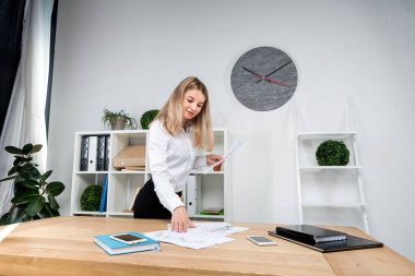 Tema iş kadını iş başında. Güzel genç kafkas kadın iş adamı çalışma ayakta tablo yakınındaki ofiste denetler kağıt üzerinde düzenlemeler finansal grafikler