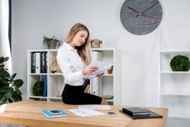 Tema iş kadını iş başında. Kağıt üzerinde düzenlemeler finansal grafikler kontrol ofiste, tabloda kenarında oturan çalışma güzel genç seksi beyaz kadın iş adamı