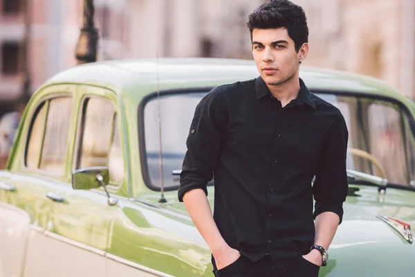 Retrato, guapo, hombre, modelo, morena raza mediterránea hombre turco se encuentra cerca de un coche retro de color verde posando en una camisa negra y jeans en la ciudad —  Fotos de Stock