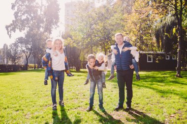 Tema aile etkin boş dışında doğada. büyük beyaz dört çocuklu bir aile. Annem ve babam aktif rahatlatıcı. çimenlerin üzerinde evi Parkı hayattan zevk. Arka omuz çocuklara top rulo