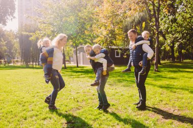 Tema aile etkin boş dışında doğada. büyük beyaz dört çocuklu bir aile. Annem ve babam aktif rahatlatıcı. çimenlerin üzerinde evi Parkı hayattan zevk. Arka omuz çocuklara top rulo