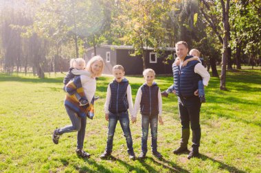 Tema aile etkin boş dışında doğada. büyük beyaz dört çocuklu bir aile. Annem ve babam aktif rahatlatıcı. çimenlerin üzerinde evi Parkı hayattan zevk. Arka omuz çocuklara top rulo