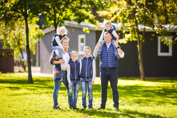 Thema familie actieve vrije tijd buiten in de natuur. grote blanke familie met vier kinderen. Pappa en mamma actief ontspannen. genieten van het leven in het park in de buurt van huis op gras. Kinderen op achterkant schouders roll bovenop — Stockfoto