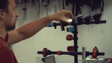 Genç bir beyaz adam barınağın duruyor ve seçer, presler düğmesine ve geri yanıp sönen ışık Bisiklet mağazasında yolda güvenli bir sürüş için bisiklet devre dışı bırakır