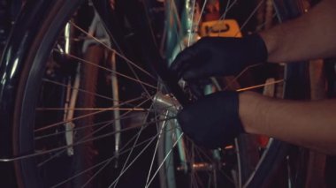 Tema küçük işletme bisiklet onarımı. Koruyucu gözlük takan genç bir beyaz esmer adam, eldiven ve önlük tamir ve bisiklet Modguards bir garaj atölyede yükleme için bir El aracını kullanır