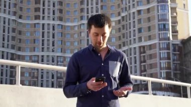 Konu işadamı kızgın telefonla konuşuyor. Genç Beyaz esmer erkek gömlek. Küçük işletme işçisi. Bir meslek. Satış Müdürü. Emlakçı smartphone kullanır. Duygu öfke ve nefret karşı bina