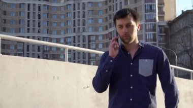 Konu işadamı kızgın telefonla konuşuyor. Genç Beyaz esmer erkek gömlek. Küçük işletme işçisi. Bir meslek. Satış Müdürü. Emlakçı smartphone kullanır. Duygu öfke ve nefret karşı bina