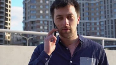 Konu işadamı kızgın telefonla konuşuyor. Genç Beyaz esmer erkek gömlek. Küçük işletme işçisi. Bir meslek. Satış Müdürü. Emlakçı smartphone kullanır. Duygu öfke ve nefret karşı bina