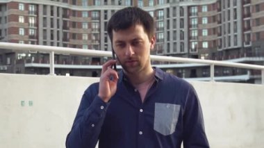 Konu işadamı kızgın telefonla konuşuyor. Genç Beyaz esmer erkek gömlek. Küçük işletme işçisi. Bir meslek. Satış Müdürü. Emlakçı smartphone kullanır. Duygu öfke ve nefret karşı bina
