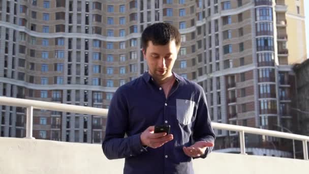 El sujeto de negocios enojado habla por teléfono. Joven morena caucásica hombre de camisa. Trabajadora de pequeñas empresas. Profesión. Gerente de ventas. Realtor utiliza smartphone. Emoción ira y odio contra la construcción — Vídeos de Stock