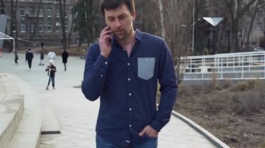 Tema adam ve sosyal ağlar. Beyaz delikanlı, gömlek, siyah saçlı bir adam sokakta bir kulak-el telefon kullanarak yürüyor. adam aramak için öğrenci dinlenme yerine bir cep telefonuyla konuşuyor