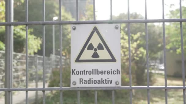 A warning sign of a radioactive hazard in German hangs on a fence enclosing a territory not safe for people. Information about the possibility of radiation exposure. Sunny, close-up — Stock Video