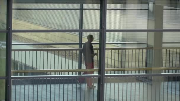 19 жовтня 2018. Німеччина Helios Klinikum Krefeld. Доктор лікар людей прогулятися по коридору між станціями клініки на підлозі вигляд через вікно — стокове відео