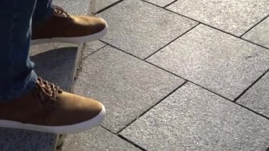 Kırmızı Ayakkabı ve kot güneşli havalarda bir şehir sokak merdivenlerde yürüyen genç bir erkekte bacaklar Close-Up