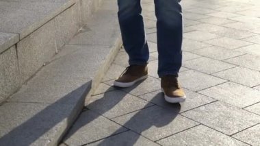 Kırmızı Ayakkabı ve kot güneşli havalarda bir şehir sokak merdivenlerde yürüyen genç bir erkekte bacaklar Close-Up