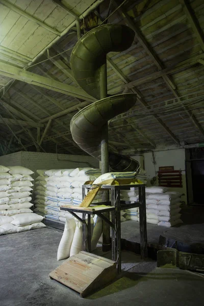 El tema de la producción y el procesamiento. Mecanismos en la antigua planta de baja tecnología para la producción de grano. Tiempos de fábrica de la Unión Soviética. Transporte de mercancías en la empresa . —  Fotos de Stock