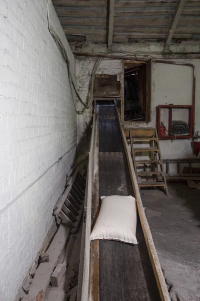 El tema de la producción y el procesamiento. Mecanismos en la antigua planta de baja tecnología para la producción de grano. Tiempos de fábrica de la Unión Soviética. Transporte de mercancías en la empresa . —  Fotos de Stock