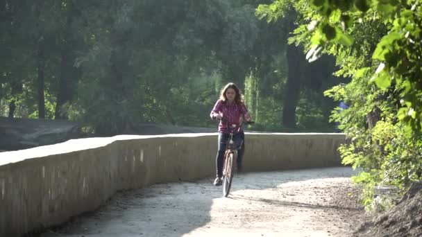 主题生态自行车运输。年轻的高加索妇女骑在公园附近的一个公园的土路上, 在阳光明媚的天气租一辆橙色自行车在秋天 — 图库视频影像