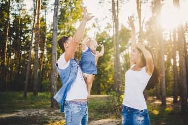 Aile anne, baba ve kızı oturur baba omuzlarında ve veliler ormandaki niteliğine yaz gün batımında öpücük