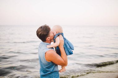Tema mutlu babalık. Bir çocuk bir yıl yaz ufuk Deniz Manzaralı kumlu bir plaj üzerinde yürümeye başlayan herhangi bir kızı çocuk tutan yalnız baba Beyaz delikanlı