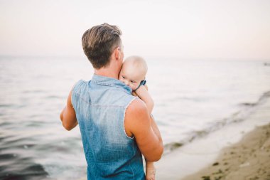 Tema mutlu babalık. Bir çocuk bir yıl yaz ufuk Deniz Manzaralı kumlu bir plaj üzerinde yürümeye başlayan herhangi bir kızı çocuk tutan yalnız baba Beyaz delikanlı