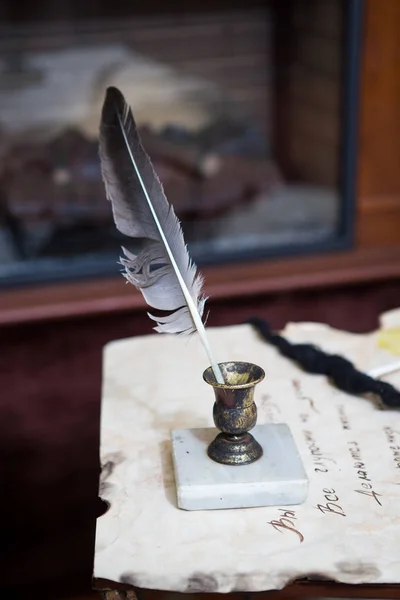 Pluma de pluma antigua, libros y tintero vintage en el escritorio de madera en la antigua oficina contra el fondo de la estantería y los rayos de luz. Antecedentes conceptuales sobre historia, educación, literatura — Foto de stock gratuita