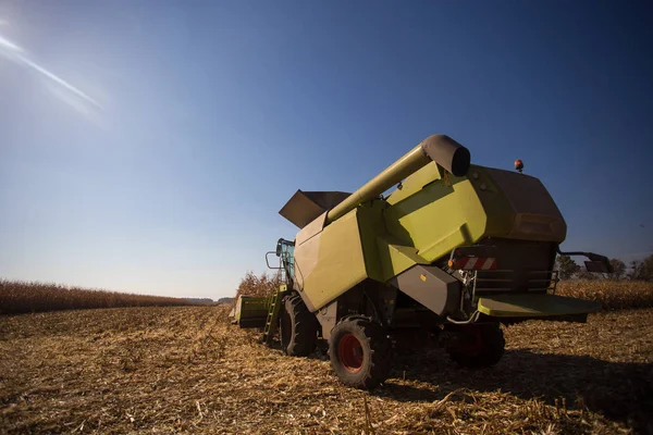 The theme is agriculture. A modern combine harvester in the field performs grain harvesting on a sunny day against a blue sky. Farm and automation using machines. — Stock Photo, Image