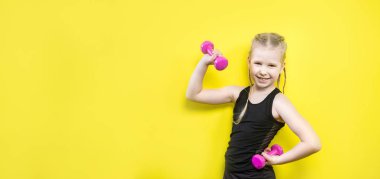 Tema spor ve sağlık. Gülümseme ile sarı arka plan üzerinde poz pigtails kız güzel çocuk. küçük atlet holding pembe dambıl. Banner reklam, metin kopya alanı alan için