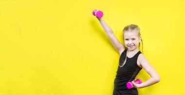 Tema spor ve sağlık. Gülümseme ile sarı arka plan üzerinde poz pigtails kız güzel çocuk. küçük atlet holding pembe dambıl. Banner reklam, metin kopya alanı alan için